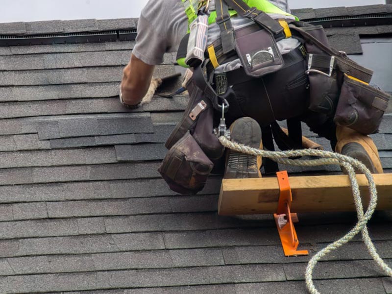 A worker installing shingles on a roof.